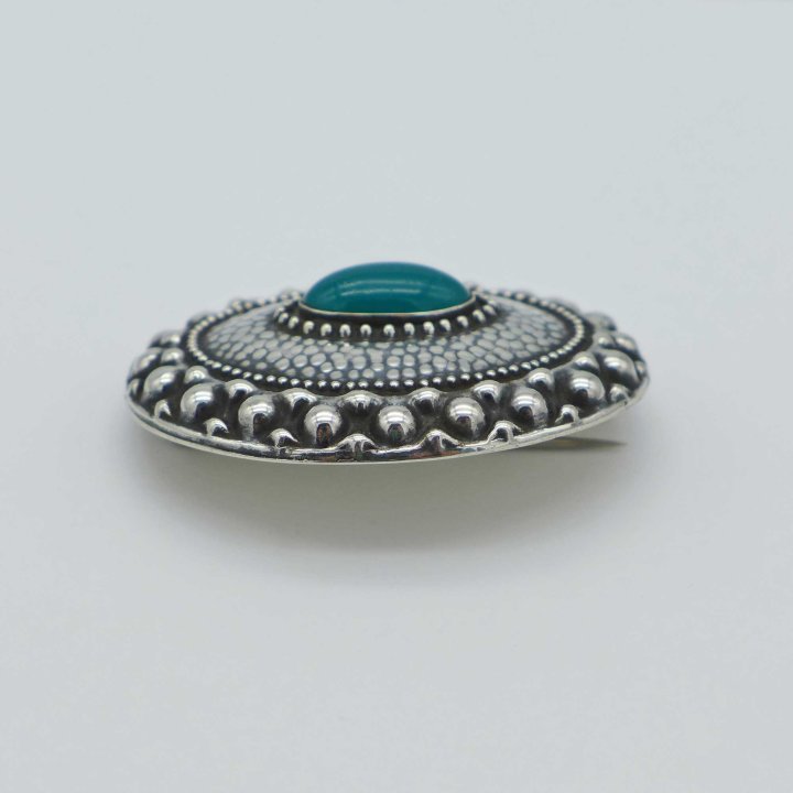 Geared silver brooch with green paste